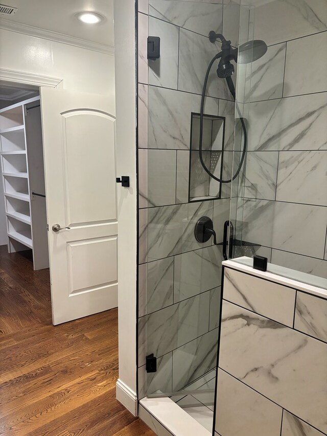 full bath with visible vents, crown molding, a shower stall, and wood finished floors