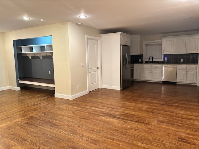 kitchen featuring baseboards, white cabinets, decorative backsplash, dark wood-style flooring, and stainless steel appliances