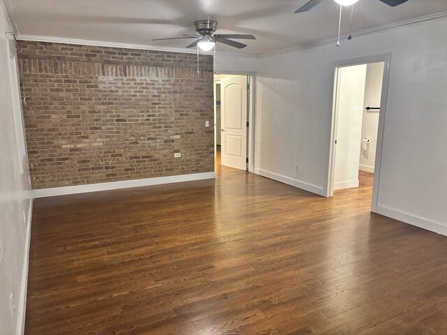 spare room with brick wall, ornamental molding, dark wood finished floors, and baseboards