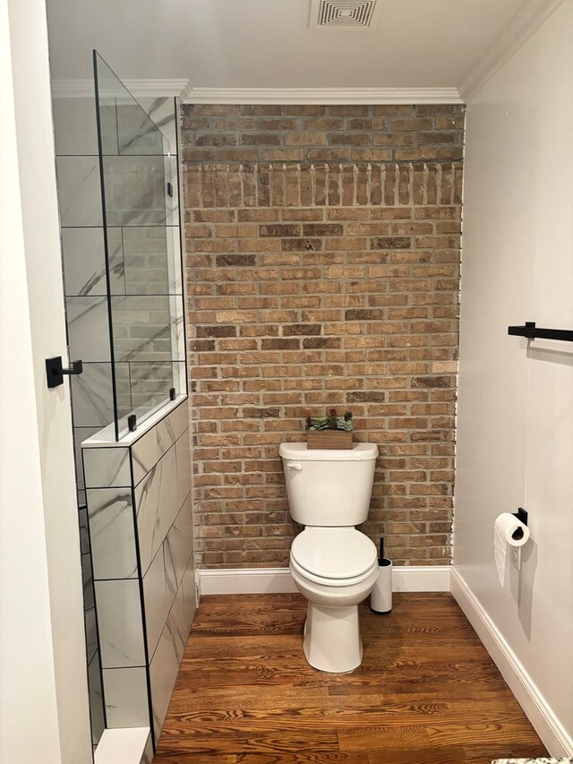 bathroom with ornamental molding, toilet, and wood finished floors