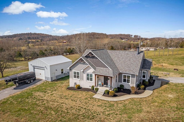 view of front of property with a front yard, a detached garage, an outdoor structure, and roof with shingles