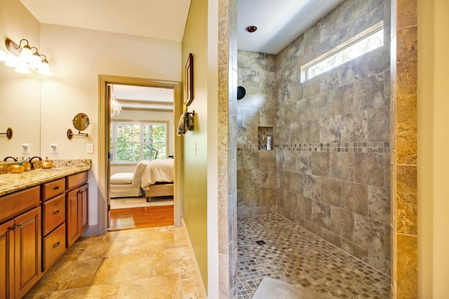 ensuite bathroom featuring stone finish floor, a tile shower, vanity, and ensuite bathroom