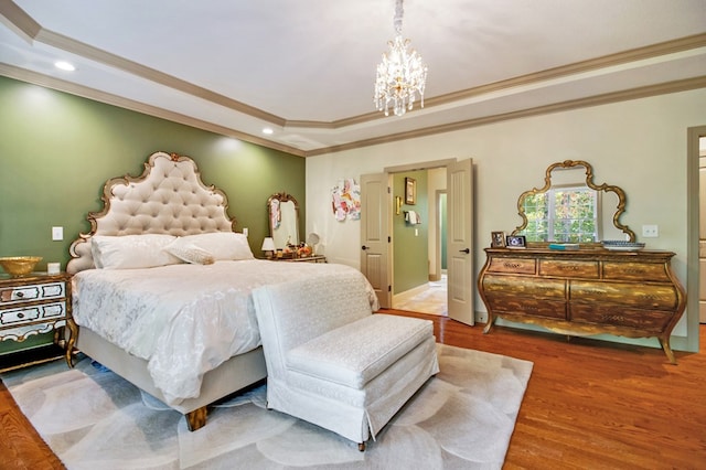 bedroom featuring a notable chandelier, crown molding, a tray ceiling, and wood finished floors