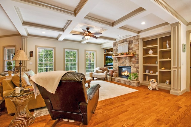 living room with a stone fireplace, coffered ceiling, wood finished floors, and beam ceiling