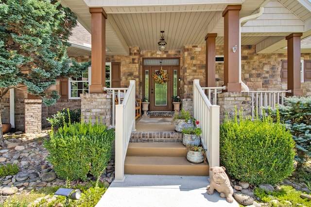 view of exterior entry featuring stone siding and covered porch