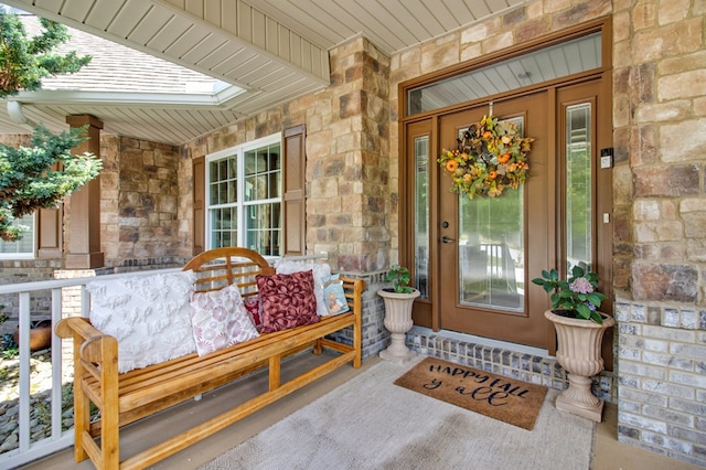 doorway to property with covered porch and stone siding