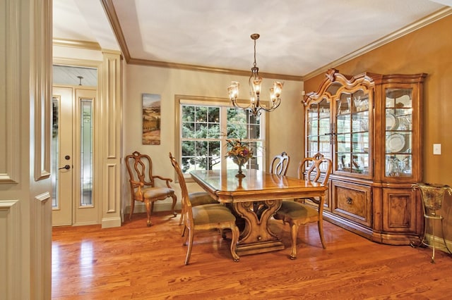 dining room featuring baseboards, ornamental molding, light wood-style flooring, and an inviting chandelier