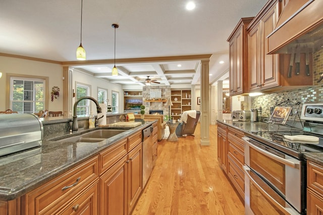 kitchen featuring pendant lighting, stainless steel appliances, custom range hood, a sink, and dark stone counters