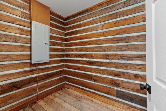 interior space featuring electric water heater, wooden walls, a wainscoted wall, light countertops, and stone finish floor