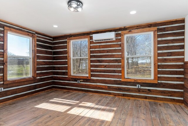 spare room featuring a wall unit AC, recessed lighting, wood finished floors, and wainscoting