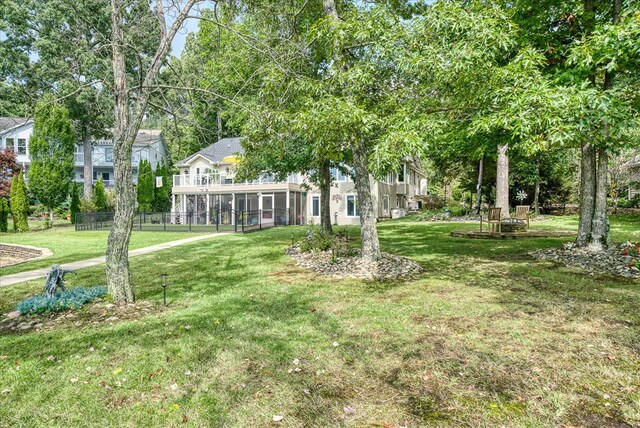 view of yard with an outdoor fire pit, fence, and a sunroom