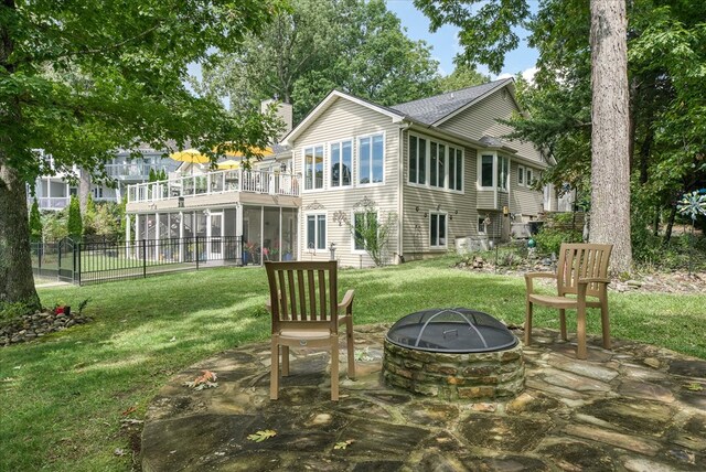 rear view of house featuring an outdoor fire pit, a chimney, a lawn, and a balcony