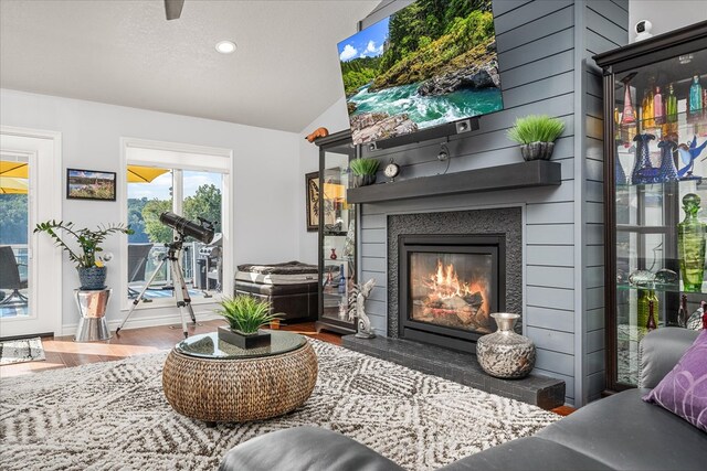 living area with vaulted ceiling, wood finished floors, and a glass covered fireplace