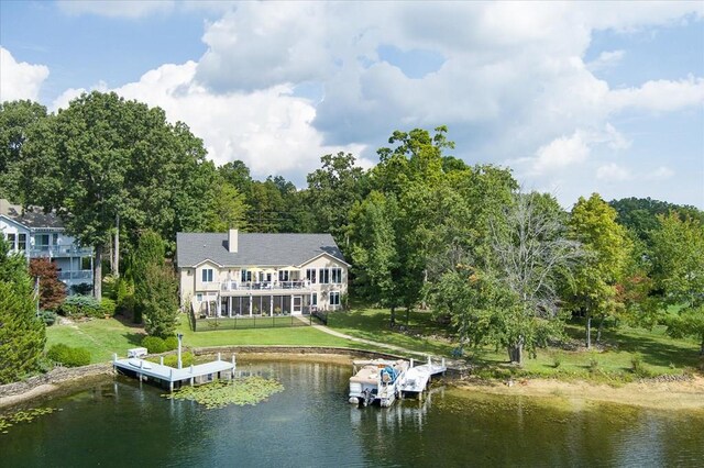 back of house with a water view, a lawn, and a chimney