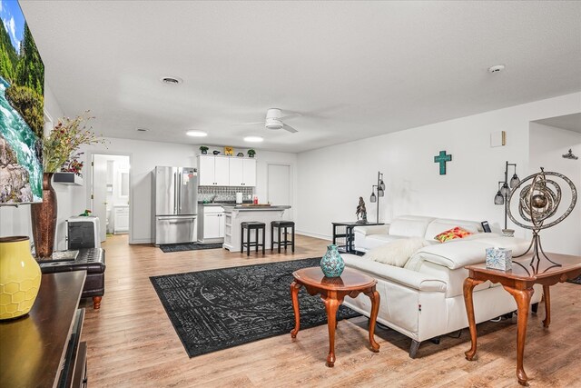 living area featuring ceiling fan, baseboards, visible vents, and light wood-style floors