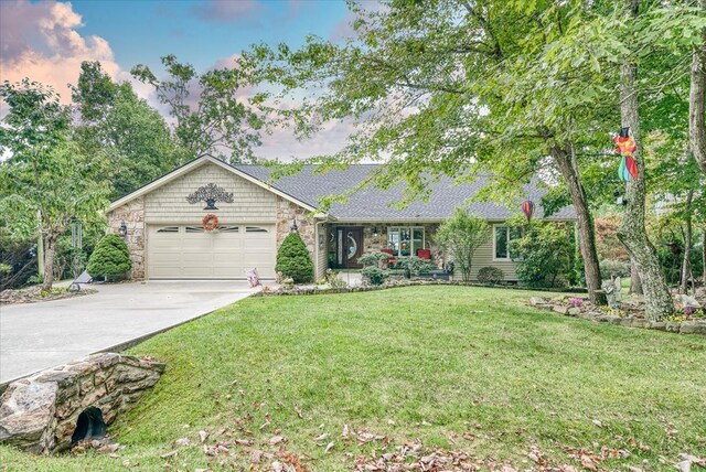 ranch-style home with stone siding, concrete driveway, a yard, and an attached garage