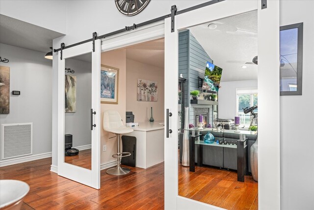 interior space with baseboards, a barn door, visible vents, and wood finished floors