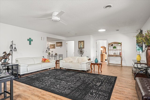 living area featuring a ceiling fan, visible vents, a textured ceiling, and wood finished floors