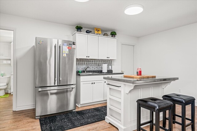 kitchen featuring a breakfast bar, a center island, dark countertops, white cabinets, and high end refrigerator