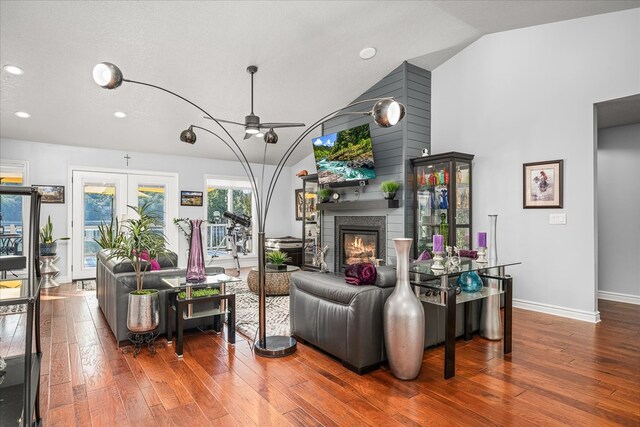 living area featuring lofted ceiling, french doors, a glass covered fireplace, and wood finished floors