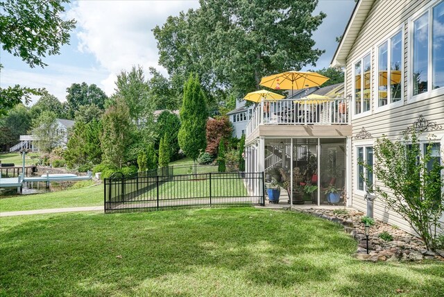 view of yard featuring a sunroom, fence, and a balcony