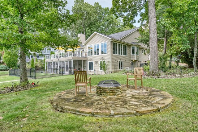 back of property with a chimney, a lawn, a fire pit, and fence