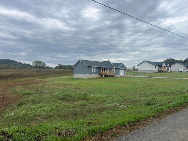 view of front of home with an attached garage, crawl space, a front yard, and a rural view