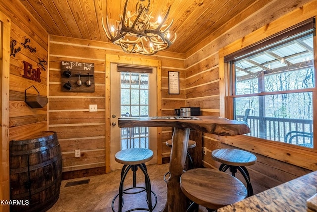 interior space featuring a chandelier, wooden walls, wood ceiling, visible vents, and a dry bar