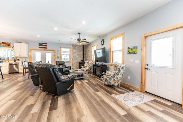 living room with baseboards, a wood stove, french doors, light wood-type flooring, and recessed lighting