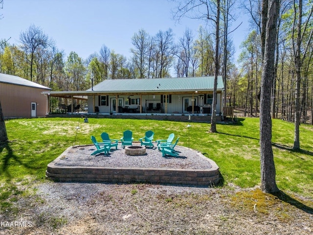 back of house featuring metal roof, a yard, a fire pit, and a patio