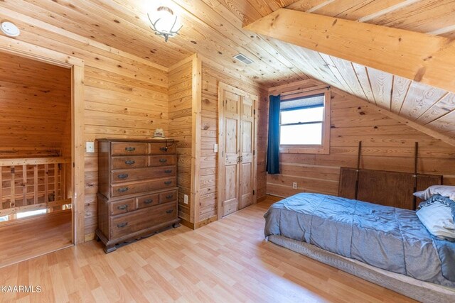 bedroom featuring visible vents, vaulted ceiling, wood walls, wood finished floors, and wooden ceiling