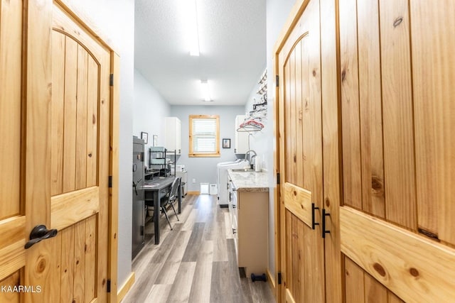 hall featuring light wood-style floors, a textured ceiling, and a sink