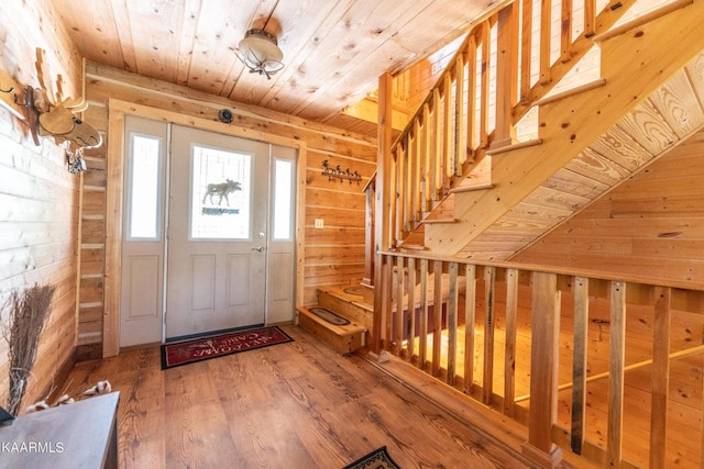 foyer featuring wooden ceiling, stairway, wood finished floors, and wood walls