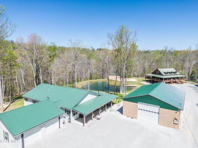 birds eye view of property featuring a water view and a wooded view