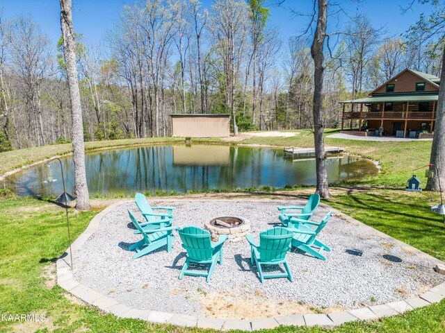 surrounding community featuring a water view, an outdoor fire pit, and a lawn