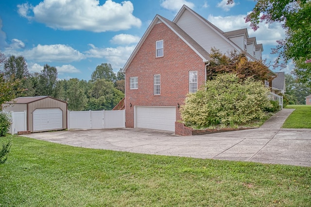 view of side of property with brick siding, fence, driveway, a lawn, and a gate