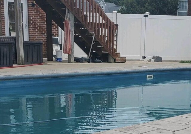 view of swimming pool featuring stairs, fence, and a fenced in pool