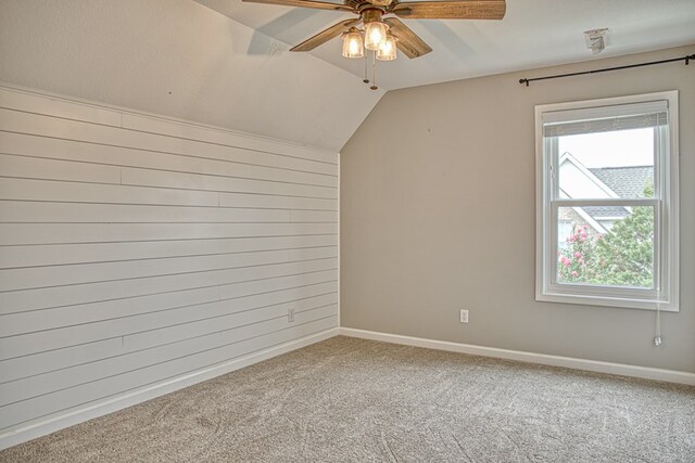 empty room featuring lofted ceiling, carpet floors, a ceiling fan, and baseboards