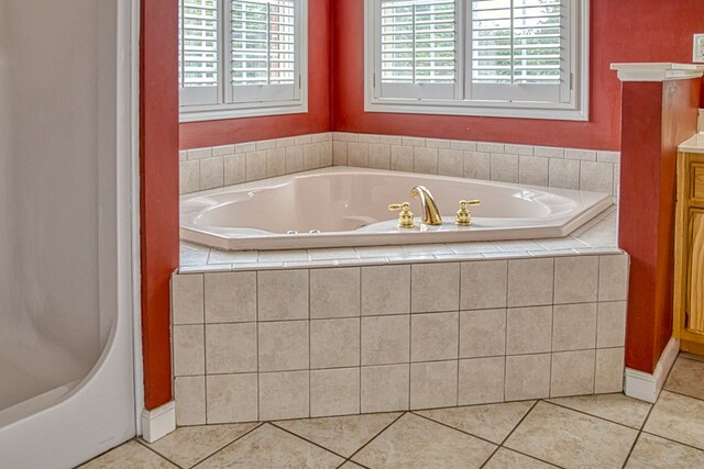 bathroom with tile patterned flooring, a garden tub, and vanity