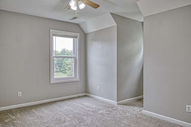 spare room with lofted ceiling, light colored carpet, visible vents, ceiling fan, and baseboards