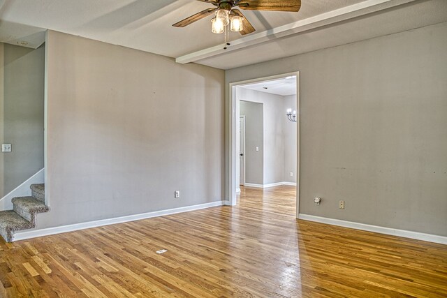 spare room featuring stairway, ceiling fan, baseboards, and wood finished floors