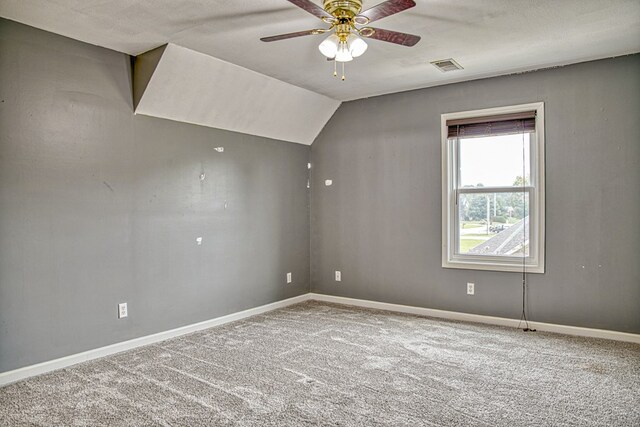 empty room with visible vents, baseboards, ceiling fan, carpet, and vaulted ceiling