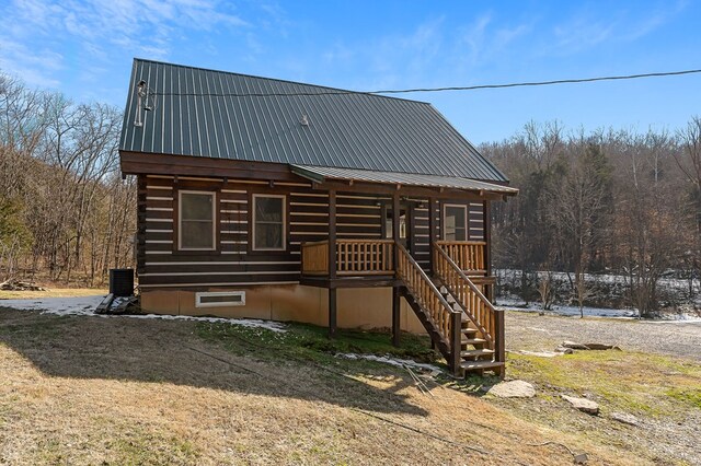 view of front of property featuring cooling unit, log exterior, metal roof, and stairway