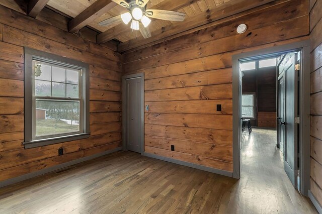 unfurnished room featuring wood ceiling, beam ceiling, wooden walls, and wood finished floors