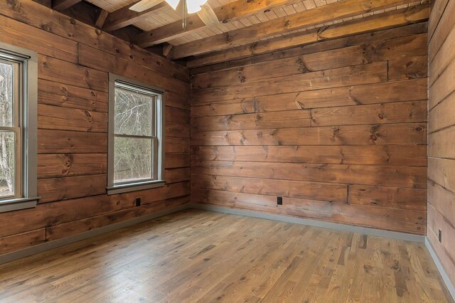 spare room with a healthy amount of sunlight, wooden ceiling, light wood-style flooring, and wooden walls