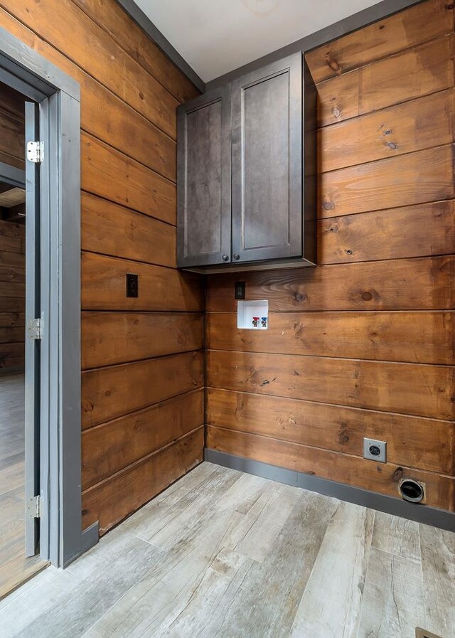 laundry room with washer hookup, cabinet space, light wood-style flooring, hookup for an electric dryer, and wood walls