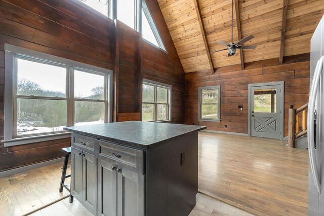 kitchen featuring plenty of natural light, wooden walls, dark countertops, and a center island