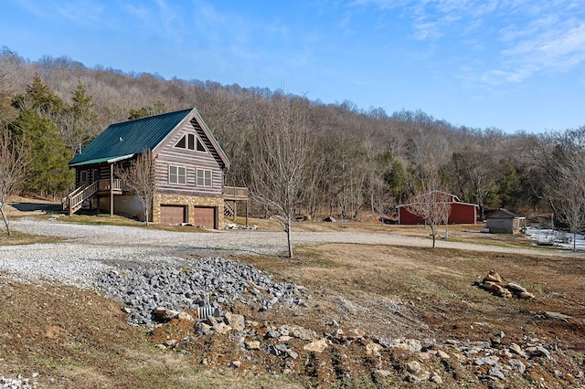 exterior space featuring driveway, a garage, and a wooded view