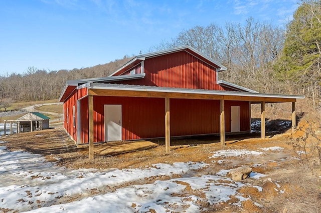 view of snowy exterior with an outdoor structure and a detached garage