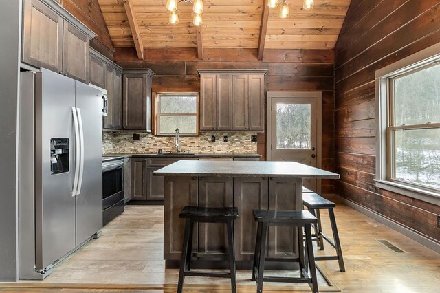 kitchen with wood ceiling, a breakfast bar, a center island, vaulted ceiling with beams, and stainless steel appliances